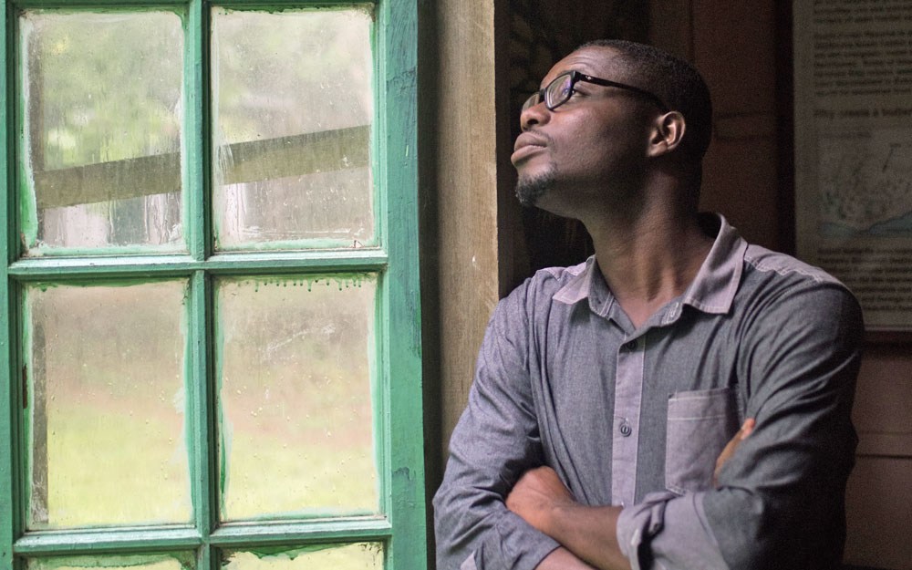 man wearing glasses looking out of a window